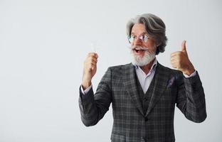 avec ampoule dans les mains. homme moderne et élégant aux cheveux gris et à la barbe à l'intérieur photo