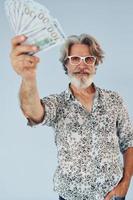 millionnaire avec de l'argent en mains. homme moderne et élégant aux cheveux gris et à la barbe à l'intérieur photo