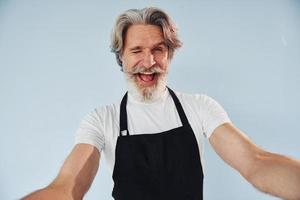 un serveur joyeux prend un selfie. homme moderne et élégant aux cheveux gris et à la barbe à l'intérieur photo