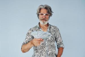 millionnaire avec de l'argent en mains. homme moderne et élégant aux cheveux gris et à la barbe à l'intérieur photo