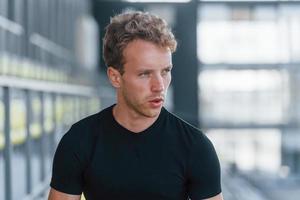 faire une pause. jeune homme sportif en chemise noire et pantalon à l'extérieur pendant la journée photo