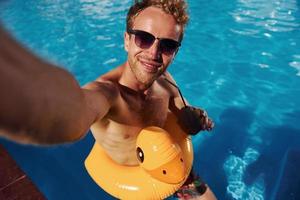 jeune homme positif se reposer à l'extérieur dans la piscine pendant la journée photo