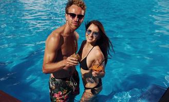 avec cocktail. joyeux couple ou amis ensemble dans la piscine en vacances photo