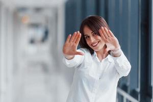 brune en chemise blanche qui marche à l'intérieur dans un aéroport ou un couloir moderne pendant la journée photo