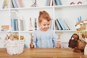 jolie petite fille jouant avec des jouets lors de la célébration des vacances de pâques à l'intérieur photo