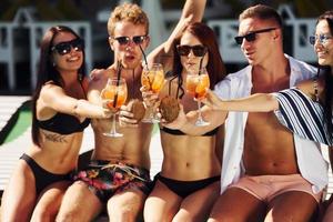 un groupe de jeunes gens heureux s'amuse dans la piscine pendant la journée photo