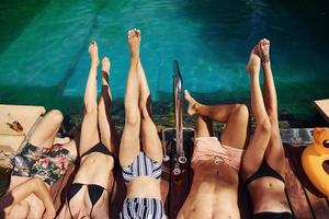 se reposer ensemble. un groupe de jeunes gens heureux s'amuse dans la piscine pendant la journée photo