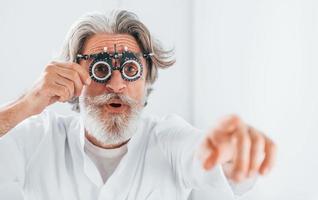 belles expressions faciales. un homme âgé aux cheveux gris et à la barbe est en clinique d'ophtalmologie photo