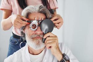 se faire tester par une travailleuse. un homme âgé aux cheveux gris et à la barbe est en clinique d'ophtalmologie photo