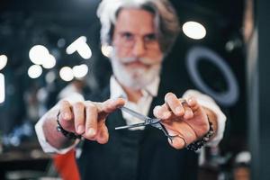 en salon de coiffure. homme âgé moderne et élégant aux cheveux gris et à la barbe est à l'intérieur photo