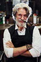 en salon de coiffure. homme âgé moderne et élégant aux cheveux gris et à la barbe est à l'intérieur photo