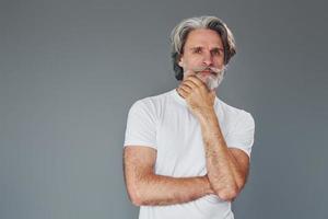 beau portrait. homme âgé moderne et élégant aux cheveux gris et à la barbe est à l'intérieur photo