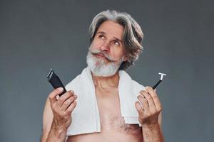 prendre soin de la barbe. homme âgé moderne et élégant aux cheveux gris est à l'intérieur photo