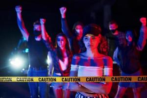 femme calme debout devant la foule. groupe de jeunes protestataires qui se tiennent ensemble. militant pour les droits de l'homme ou contre le gouvernement photo