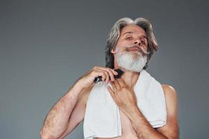 prendre soin de la barbe. homme âgé moderne et élégant aux cheveux gris est à l'intérieur photo