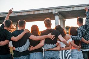 vue de derrière. groupe de jeunes amis joyeux s'amusant ensemble. faire la fête en plein air photo