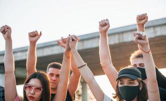 poings levés très haut. groupe de jeunes protestataires qui se tiennent ensemble. militant pour les droits de l'homme ou contre le gouvernement photo