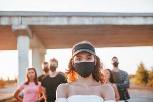 belle fille au masque. groupe de jeunes protestataires qui se tiennent ensemble. militant pour les droits de l'homme ou contre le gouvernement photo