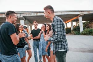 parler et rire. groupe de jeunes amis joyeux s'amusant ensemble. faire la fête en plein air photo