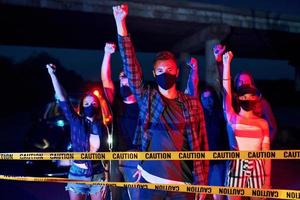 éclairage de police rouge et bleu. groupe de jeunes protestataires qui se tiennent ensemble. militant pour les droits de l'homme ou contre le gouvernement photo