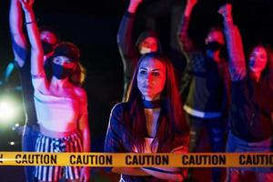 femme calme debout devant la foule. groupe de jeunes protestataires qui se tiennent ensemble. militant pour les droits de l'homme ou contre le gouvernement photo