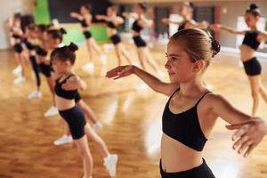 mode de vie actif. groupe d'enfants féminins pratiquant des exercices athlétiques ensemble à l'intérieur photo