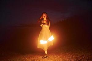 spectacle de feu par une femme en robe dans les montagnes des carpates de nuit. beau paysage photo