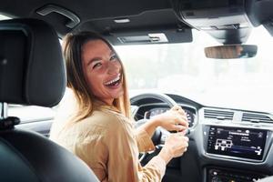 le conducteur regarde en arrière et sourit. belle jeune femme à la mode et son automobile moderne photo