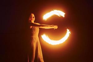 photo avec une longue exposition. spectacle de feu par une femme en robe dans les montagnes des carpates de nuit. beau paysage