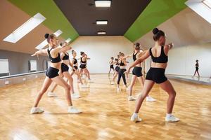 vue latérale d'un groupe d'enfants de sexe féminin qui pratiquent des exercices athlétiques ensemble à l'intérieur photo