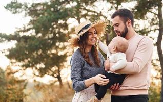 unité du peuple. une famille heureuse de mère, de famille et de petit bébé se repose à l'extérieur. belle nature d'automne ensoleillée photo