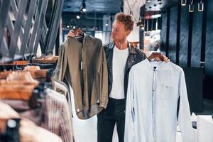 grand choix. jeune homme dans un magasin moderne avec de nouveaux vêtements. vêtements élégants et chers pour hommes photo