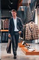 Jour de shopping. jeune homme dans un magasin moderne avec de nouveaux vêtements. vêtements élégants et chers pour hommes photo