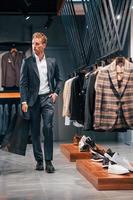 Jour de shopping. jeune homme dans un magasin moderne avec de nouveaux vêtements. vêtements élégants et chers pour hommes photo