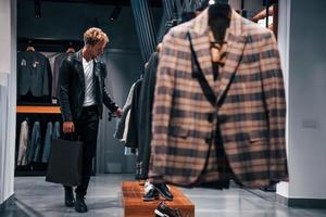 courses du week-end. jeune homme dans un magasin moderne avec de nouveaux vêtements. vêtements élégants et chers pour hommes photo
