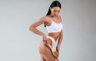 tient la brosse. femme avec un type de corps mince sportif en sous-vêtements qui est dans le studio photo