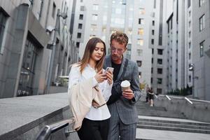 avec téléphone et boisson. femme et homme dans la ville pendant la journée. des gens bien habillés photo