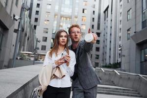 avec téléphone et boisson. femme et homme dans la ville pendant la journée. des gens bien habillés photo