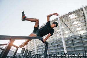 fait du parkour. jeune homme en tenue sportive s'entraîne à l'extérieur pendant la journée photo