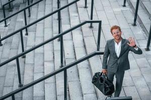 beauté urbaine. jeune homme d'affaires en tenue de soirée grise est à l'extérieur de la ville photo