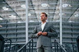 dans les escaliers du stade. jeune homme d'affaires en tenue de soirée grise est à l'extérieur de la ville photo