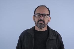 portrait d'homme barbu de 60 ans sur fond bleu avec chapeau et lunettes photo