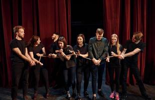 avec une corde dans les mains. groupe d'acteurs vêtus de vêtements de couleur sombre en répétition au théâtre photo