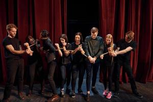 avec une corde dans les mains. groupe d'acteurs vêtus de vêtements de couleur sombre en répétition au théâtre photo