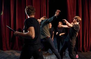 Scène de combat. groupe d'acteurs vêtus de vêtements de couleur sombre en répétition au théâtre photo