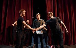 travailler ensemble. groupe d'acteurs vêtus de vêtements de couleur sombre en répétition au théâtre photo