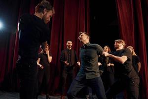 Scène de combat. groupe d'acteurs vêtus de vêtements de couleur sombre en répétition au théâtre photo