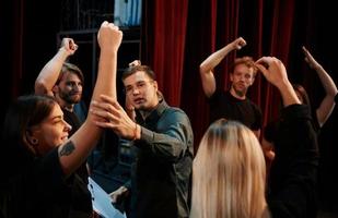 pratique en cours. groupe d'acteurs vêtus de vêtements de couleur sombre en répétition au théâtre photo