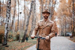 dans le parc en scooter électrique. jeune mannequin en vêtements à la mode est à l'extérieur dans le parc pendant la journée photo