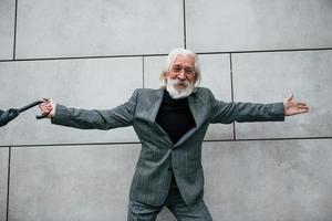 tient un parapluie. homme d'affaires senior en vêtements formels, aux cheveux gris et à la barbe est à l'extérieur photo